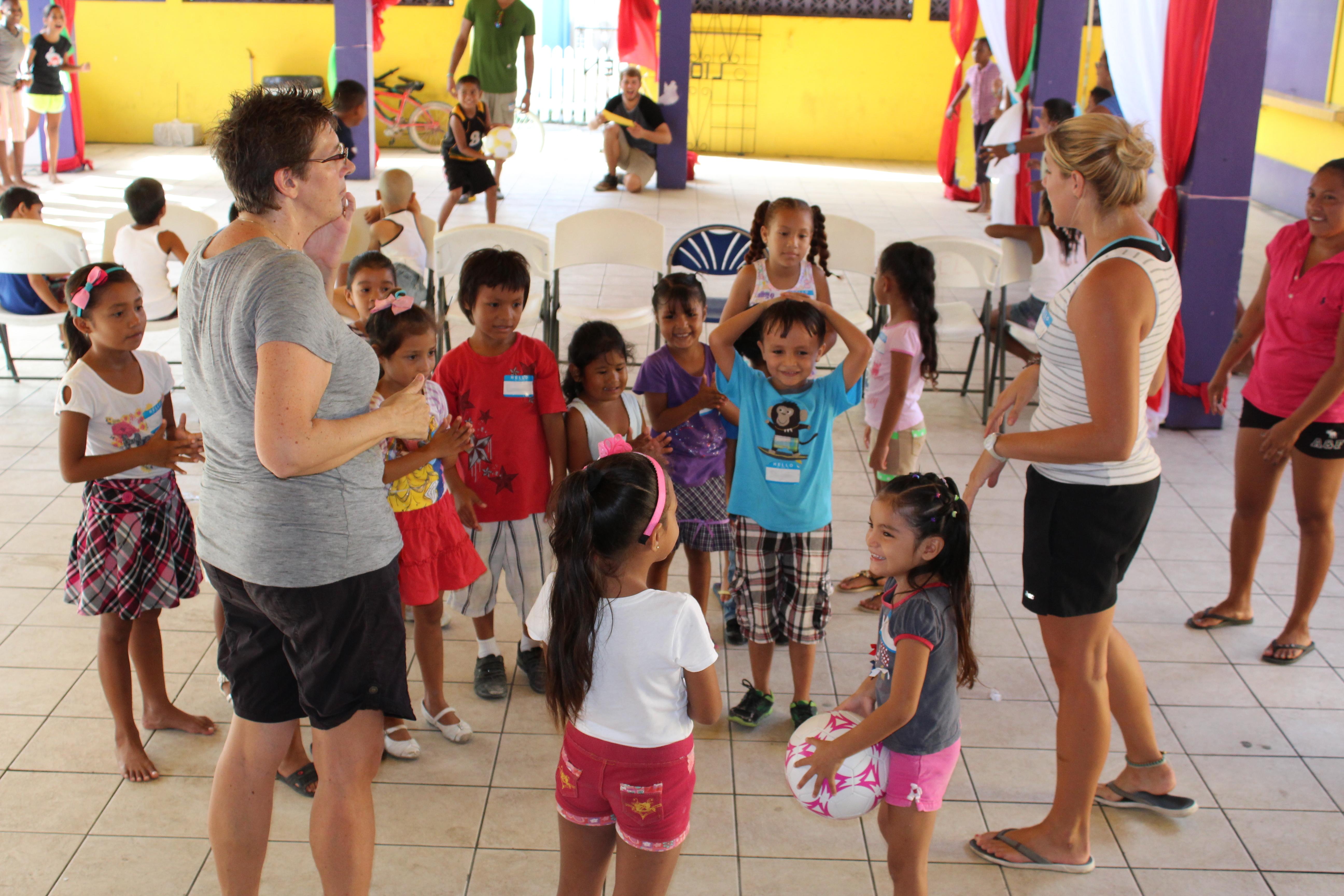 Two Projects Abroad Childcare volunteers teach children how to play a game with a ball in Belize. A group of children are being taught how to play ball games by volunteers working with children in Belize.